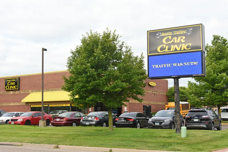 Apple Valley Car Clinic building and roadside sign with customer cars parked out front