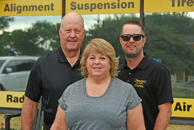 Doug, Karen and their son Justin, owner of Apple Valley Car Clinic, smiling outside the shop