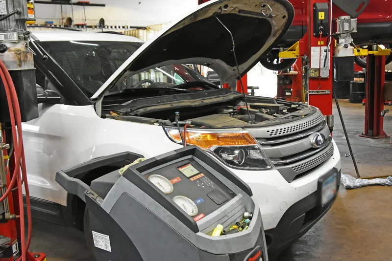 Auto A/C service machine connected to a white Ford Explorer with the hood open