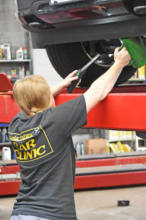 Apple Valley Car Clinic technician working under a vehicle raised on a lift