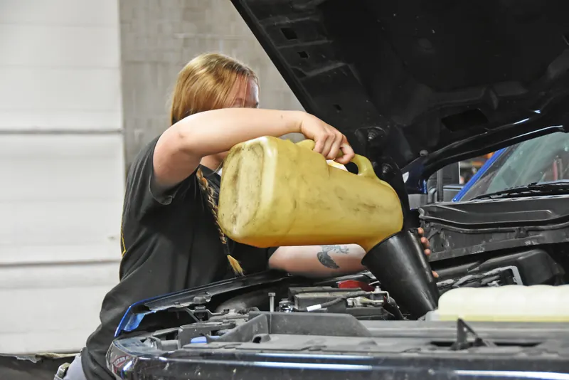 Technician pouring fresh motor oil into an engine during an oil change