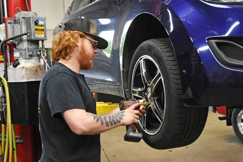 Technician using an impact wrench on a car wheel at Apple Valley Car Clinic